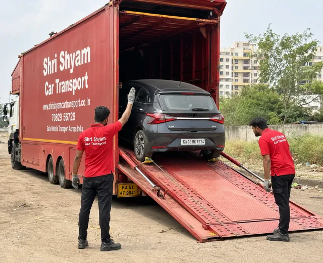 Crew guiding a car up a hydraulic carrier ramp | Shri Shyam Car Transport